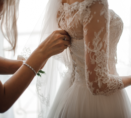 A woman helps put on a wedding dress