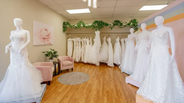 an array of wedding dresses hanging in a fitting room with comfortable seating