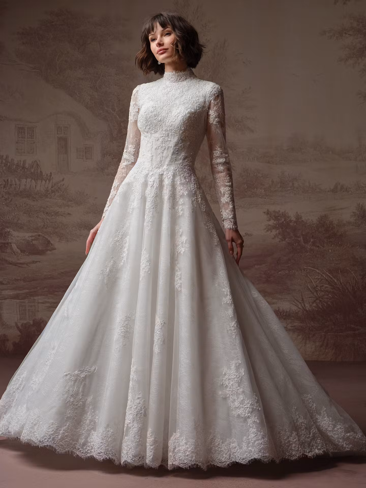 Dominique by Maggie Sottero modest lace A-line wedding dress with a high neckline, illusion long sleeves, basque waist, Chantilly lace, and hidden pockets.