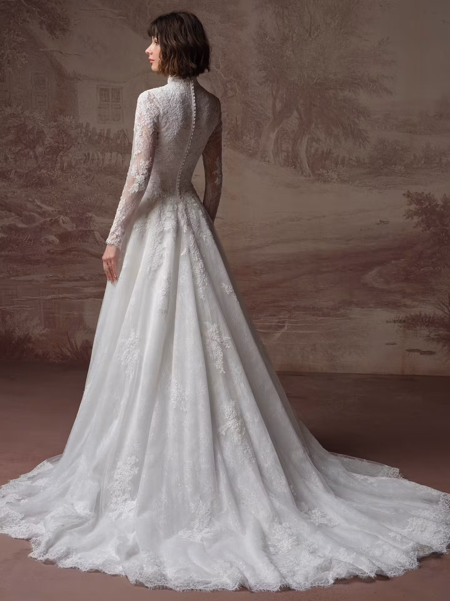 Dominique by Maggie Sottero modest lace A-line wedding dress with a high neckline, illusion long sleeves, basque waist, Chantilly lace, and hidden pockets.