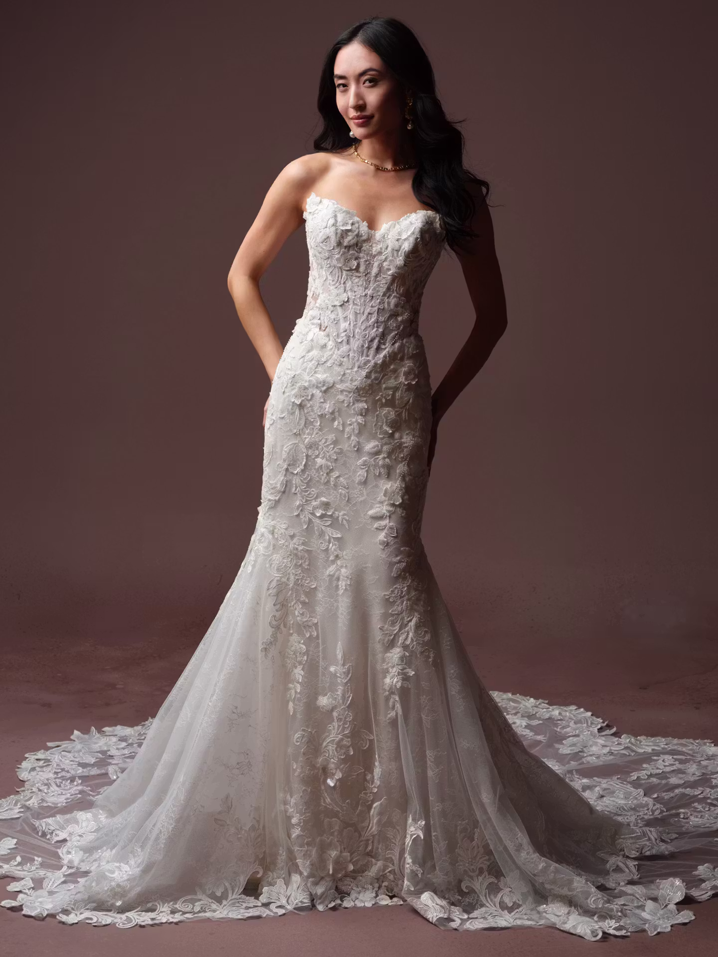 Estelle by Maggie Sottero beaded fit and flare wedding dress with a deep illusion cat eye neckline, basque waist, Chantilly lace, glitter tulle, and dramatic petal train.