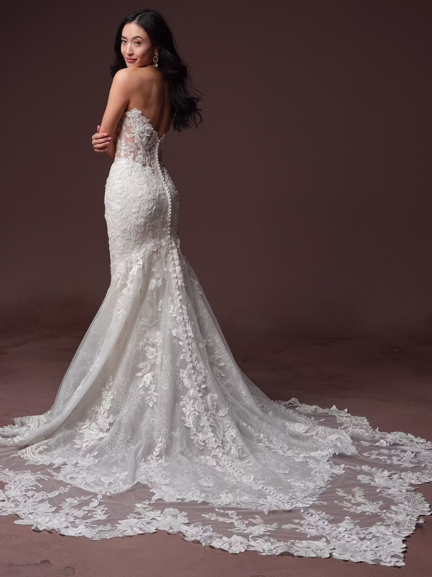 Estelle by Maggie Sottero beaded fit and flare wedding dress with a deep illusion cat eye neckline, basque waist, Chantilly lace, glitter tulle, and dramatic petal train.