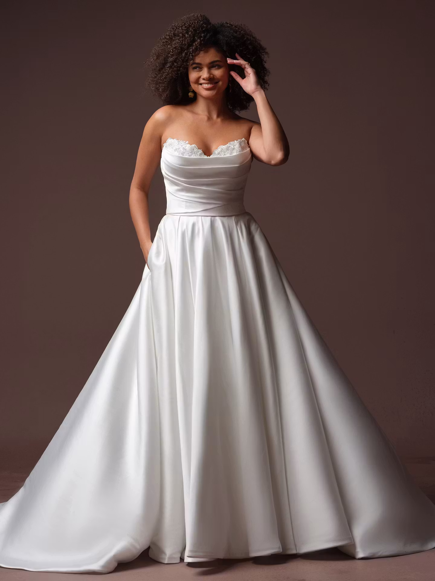 Daphne by Rebecca Ingram draped Mikado A-line wedding dress with a sweetheart neckline, subtle beaded lace, hidden pockets, and optional off-the-shoulder sleeves.