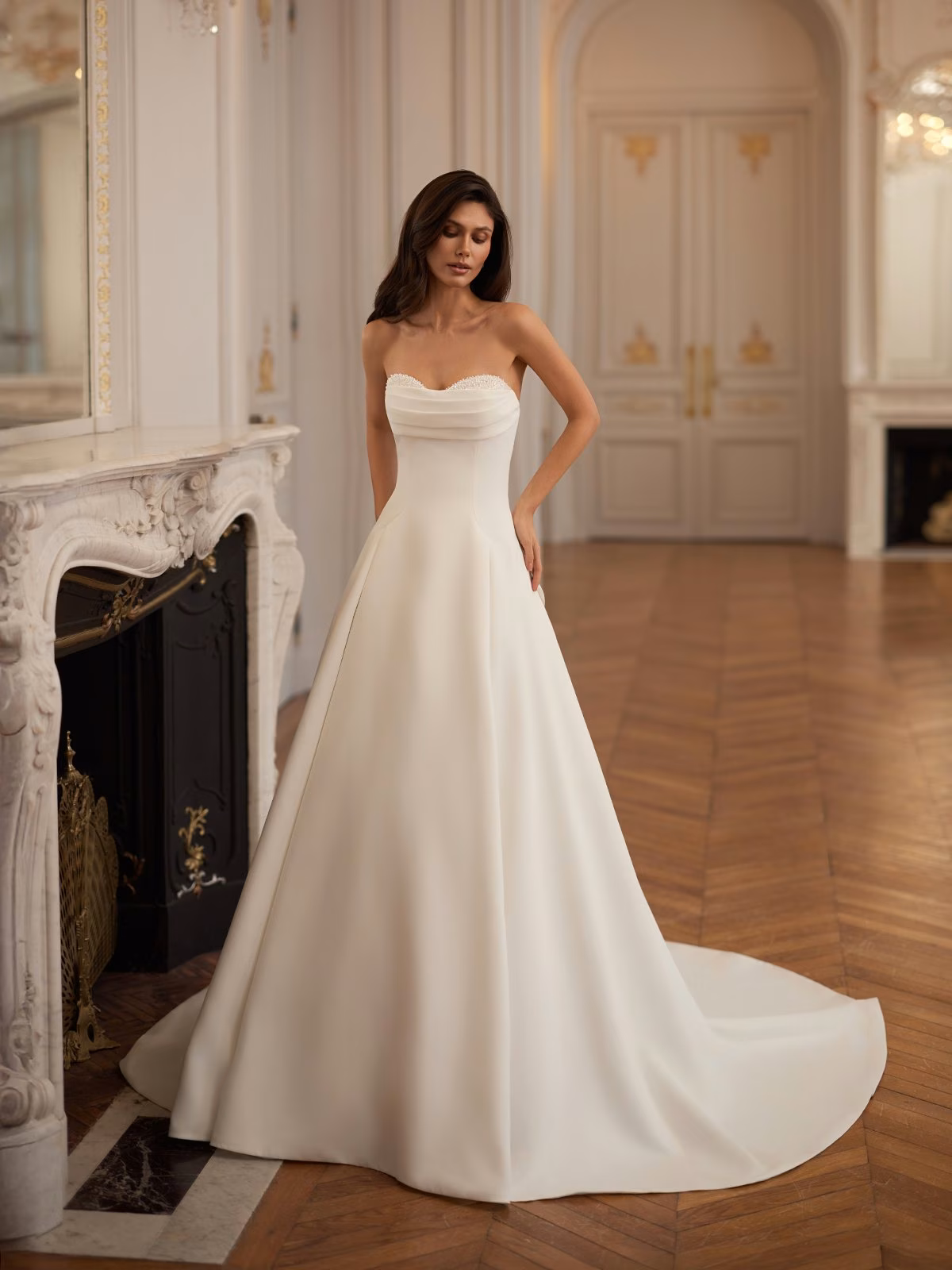 Annie by Moonlight Bridal crepe A-line wedding dress with a ruched sweetheart neckline, detachable bow, open back, and chapel train.