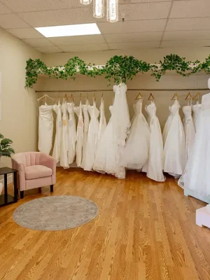 an array of wedding dresses hanging in a fitting room with comfortable seating